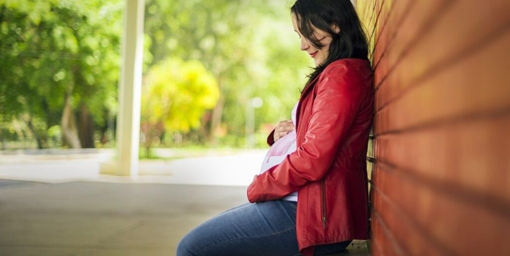 pregnant woman leaning on wall