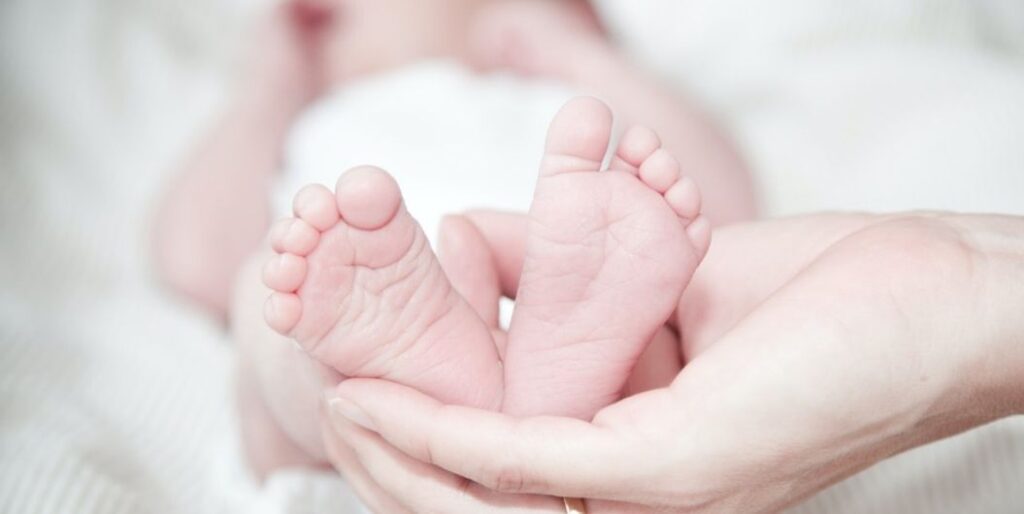 baby feet held by one hand