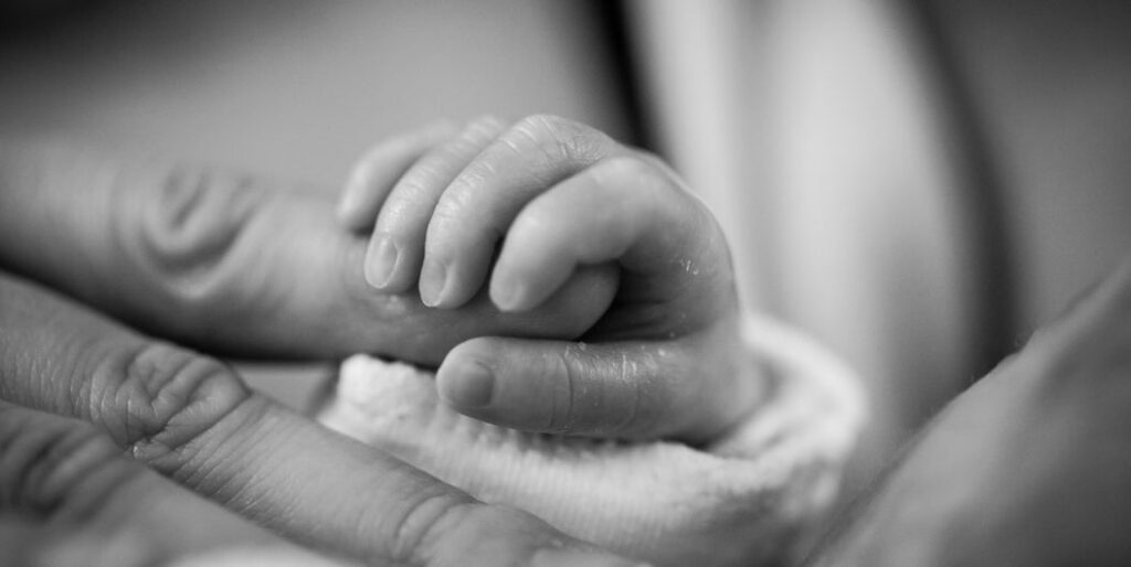 infant holding mother's finger