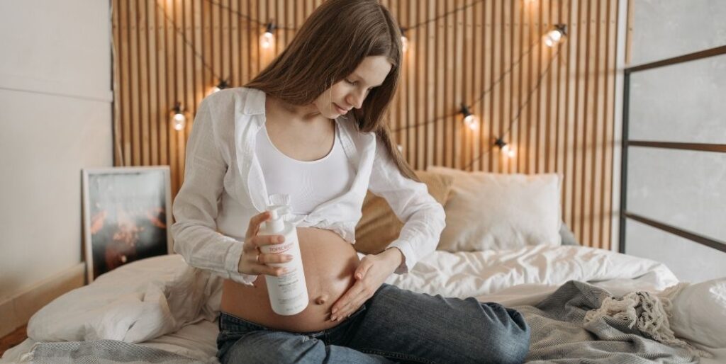 pregnant woman applying lotion on her belly