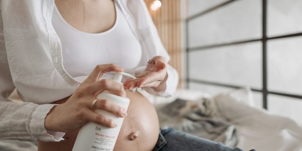 pregnant woman applying lotion on belly