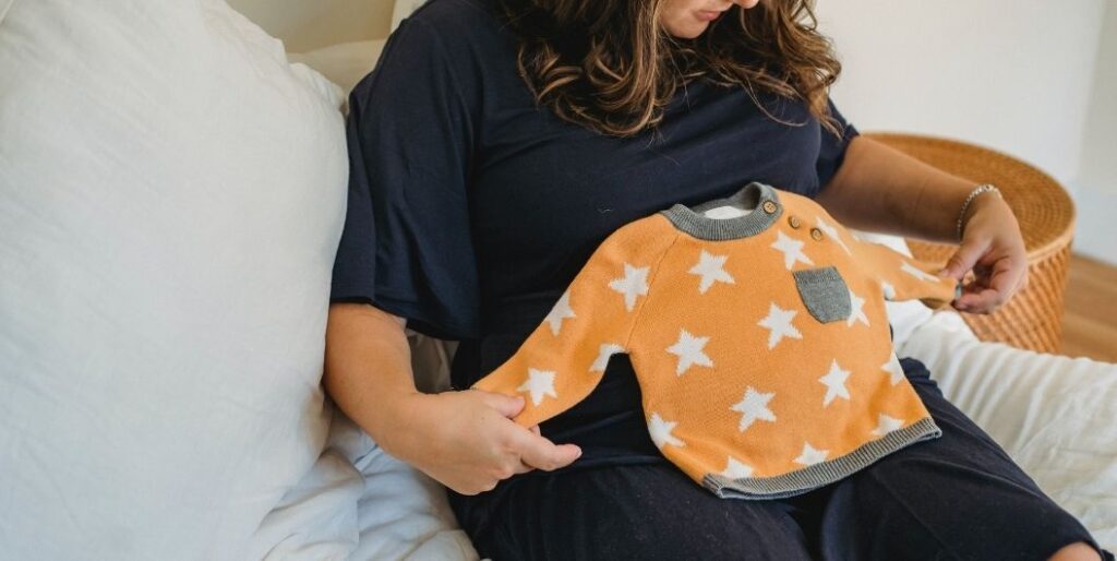 pregnant woman with baby clothes