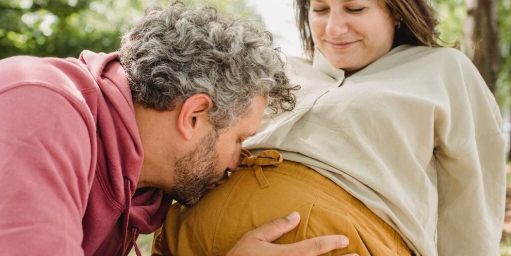 man kissing pregnant woman's belly